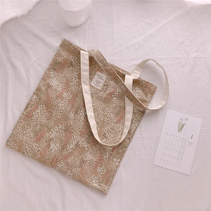 Detailed top view of a floral cotton canvas tote bag on a soft white draped fabric