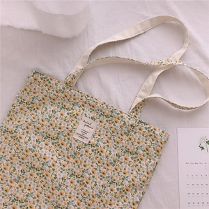 Detail of floral canvas tote bag with woven handles and vintage aesthetic label
