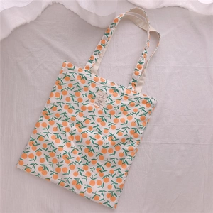 Detail of fresh orange print cotton tote bag with vintage text label on white fabric