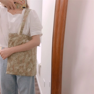 Detail of vintage floral canvas tote bag with small white flower patterns and shoulder strap