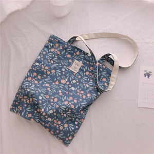Detail of floral canvas tote bag with pink flowers, woven handle and woven label
