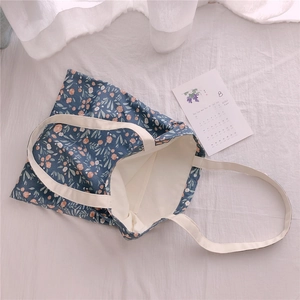 Detail of floral canvas tote bag showing interior pocket and cream webbing handles