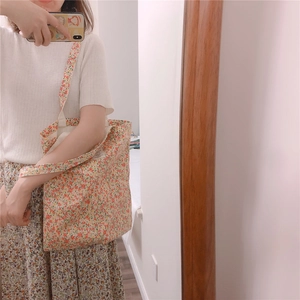 Detail of floral canvas tote bag with delicate red flower patterns and woven side label