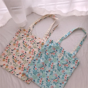 Detail view of floral cotton tote bags with embroidered labels and fabric texture