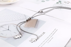 Detail of silver double-layered snake chain necklace with boy and girl pendants