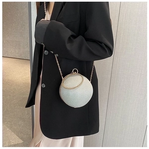 Close-up of sphere evening bag with silver glitter finish and gold chain strap