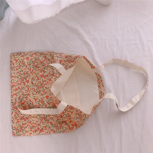 Detail of floral canvas tote bag featuring an inner pocket and sturdy white straps