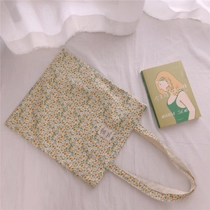 Close-up of floral cotton tote bag with white fabric label and soft yellow flower patterns