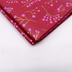 Detailansicht von dunkelrotem Seidenpapier mit rosa Beeren und goldenen Zweigen