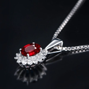 Macro shot of an oval ruby pendant featuring floral zircon halo on a classic box chain