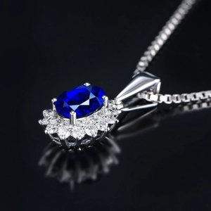Macro shot of oval blue gemstone pendant with halo of white zircon in claw setting