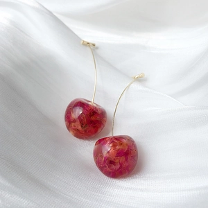 Macro detail of cherry earrings with pink resin and dried flower petals inside