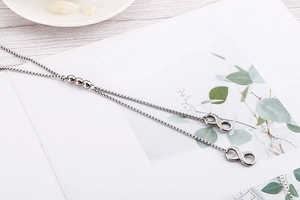 Dettaglio della collana a Y in argento con perline metalliche e pendenti a infinito