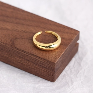 Macro shot of minimalist gold S925 sterling silver open ring on walnut wood base