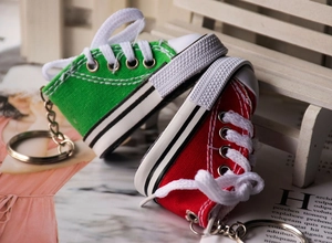 Macro detail of red and green canvas sneaker keychains on a miniature wooden bench