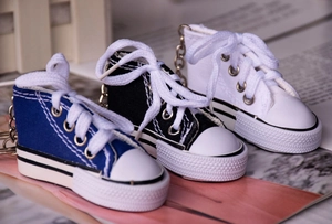 Close-up of mini canvas shoe keychains in blue black and white with metal rings