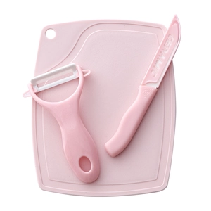 Pink ceramic kitchen knife set with cutting board and peeler on white background
