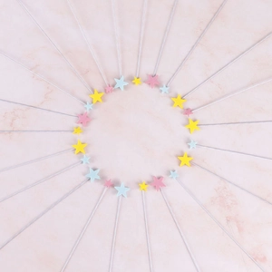 Colorful foam star cake toppers in yellow pink and blue on a marble background