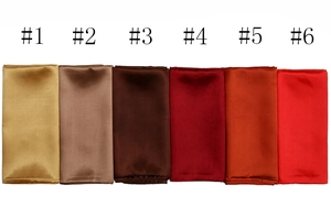 Close-up of satin silk square scarves in six warm shades from gold to deep red