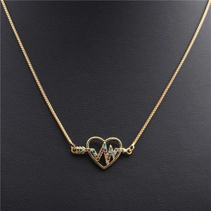 Detail of gold heart pendant necklace with multi-color zircon inlay on black background