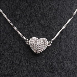 Detailed view of silver heart pendant with pave-set cubic zirconia on a black textured background