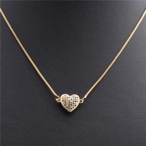 Macro shot of gold box chain featuring a multi-color zircon heart pendant on black background