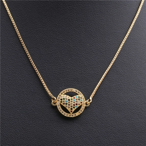 Détail d'un collier doré avec un pendentif en forme de cœur serti de pierres multicolores
