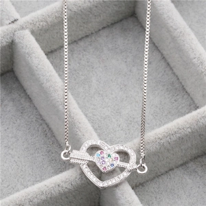Gros plan d'un pendentif double cœur en argent avec zircons colorés dans un écrin