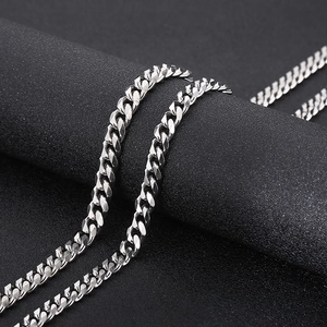 Macro detail of silver titanium steel Cuban link chain with polished edges on a dark stand