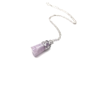 Macro detail of natural purple amethyst hexagonal crystal pendant with silver pattern