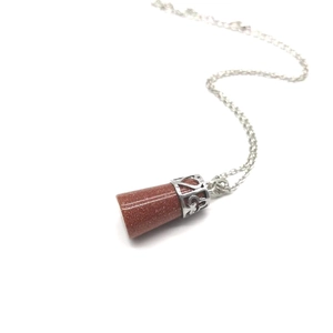 Detailed view of the conical goldstone pendant with an intricate silver filigree cap