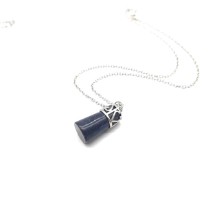 Detailed shot of a blue lapis lazuli cylinder pendant with an ornate silver metal cap