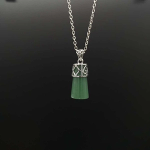 Macro view of vintage silver hollow-carved pendant with green translucent gemstone charm
