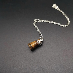 Macro detail of Tiger Eye gemstone pendant with vintage silver hollowed metal cap