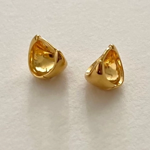 Minimalist gold oval sterling silver hoop earrings shown on a textured white background