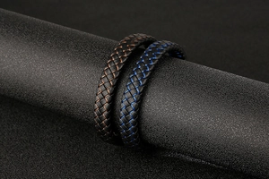 Close-up of braided leather bracelets with blue and brown stitching details for men