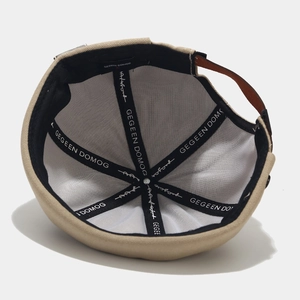 Detail view of khaki cotton skull cap interior with branded webbing and leather strap