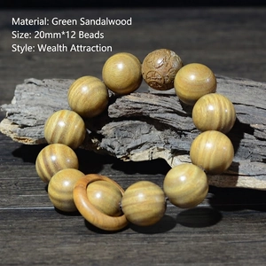 Détail de perles en bois de santal vert de 20mm avec gravure sur une branche