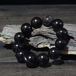 Détail macro de perles en bois noir de 20mm avec sculpture de dragon et anneau