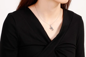 Close-up of a silver scorpion pendant necklace worn by a model on a white background