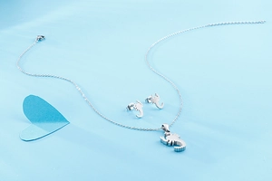Detailed view of silver scorpion necklace and matching earrings on light blue surface