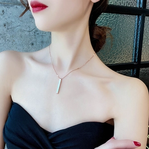 Detailed view of a rose gold bar pendant necklace on a model showing the minimalist geometric style