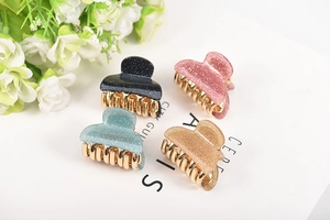 Four glitter acrylic hair claws in black, pink, blue and champagne with gold metal teeth