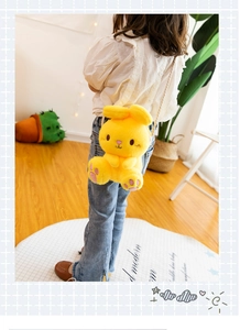 Detail of yellow plush rabbit crossbody bag worn by a child in a home setting