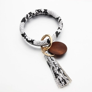 Detail van de sleutelhangerarmband in slangenleer met kwastje en ronde houten hanger