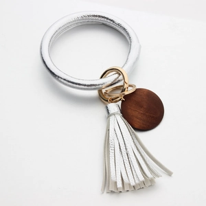 Detail of silver leather tassel and round wooden pendant on a metal bangle keychain