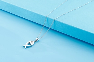 Macro detail of silver fish pendant with white diamond eye and delicate chain