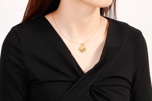 Close-up of a gold hollow four-leaf clover necklace worn on model for Mother's Day gift