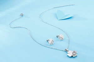 Close-up of hollow four-leaf clover jewelry set with silver necklace and stud earrings