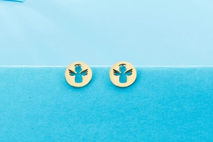 Macro detail of gold-toned angel earrings with hollow-out design and metallic shine